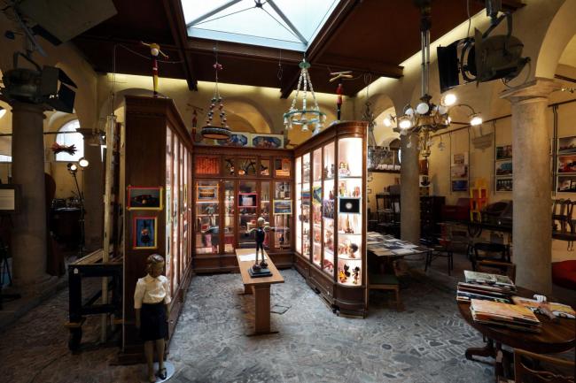 Ambiente centrale del chiostro e mobile con vetrine (da recupero di un vecchio negozio) con fotografie di Joe Nemeth; Dado Arrigo, personaggio Corriere dei Piccoli e mascotte della Ditta Arrigoni dadi da brodo su consolle di Giovanni Michelucci in legno di ciliegio e ottone per la Cassa di Risparmio di Firenze, 1953/57. Foto © Paolo Righi, Bologna.